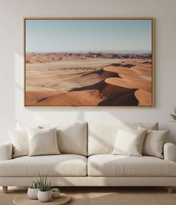 A modern living room featuring a large framed desert landscape photograph above a beige sofa, creating a warm and stylish wall decor look.
