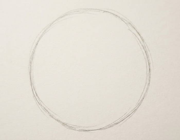 Light pencil sketch of a simple hand-drawn circle on white paper showing the first step of a peony flower drawing tutorial
