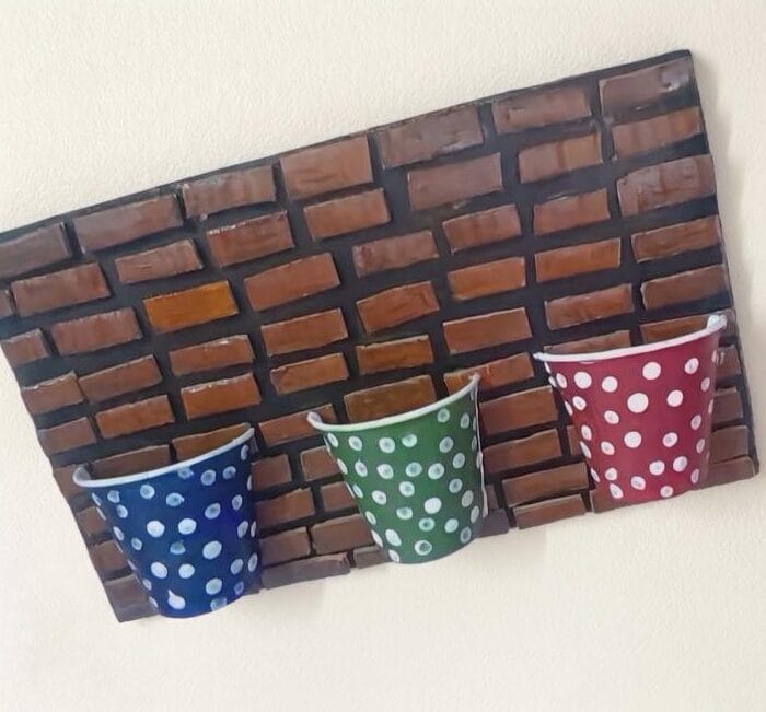 Colorful polka dot paper cups attached to a painted cardboard base, forming a creative DIY wall decor piece